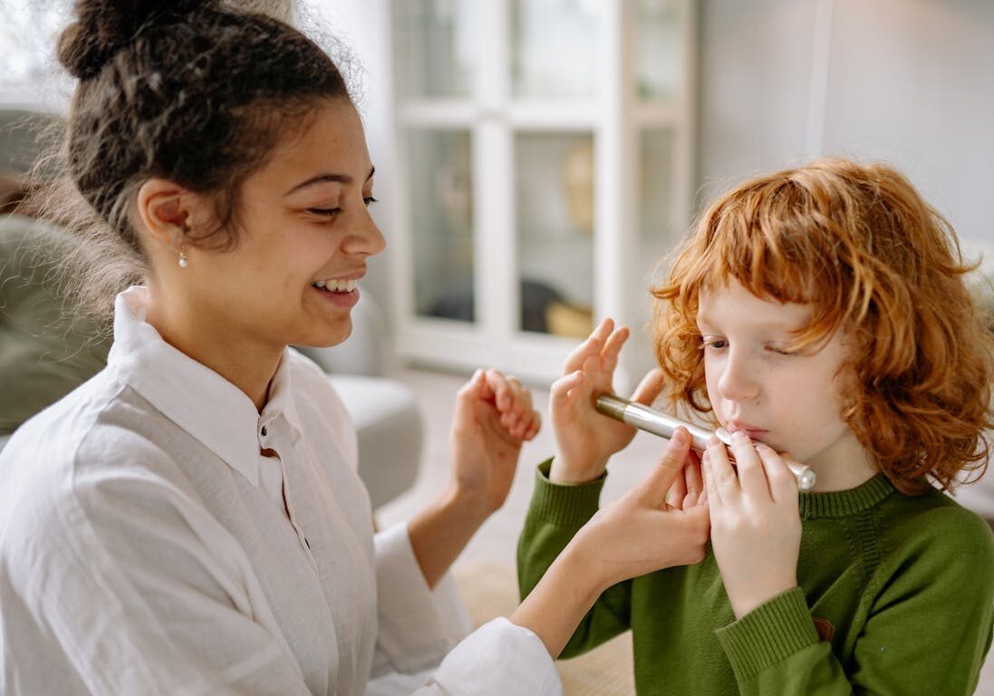 Teacher showing a child how to blow a flute